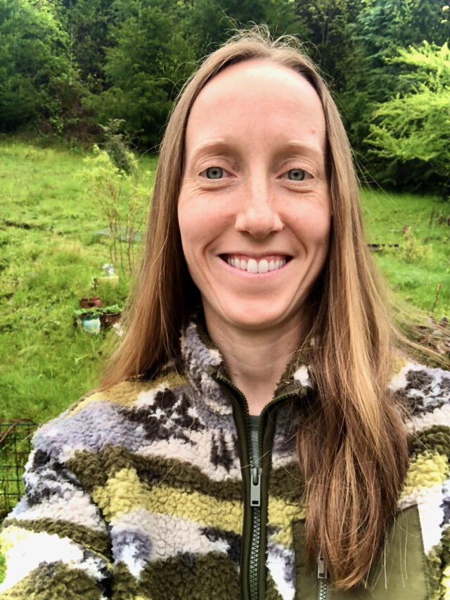 A close-up photo of Jodi Gann with a field behind her and trees at the back of the field.